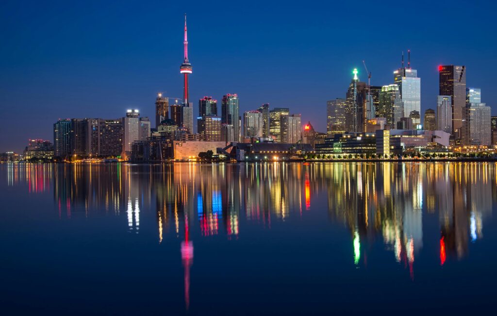 Stunning night view of Toronto skyline reflecting on water with CN Tower prominent.